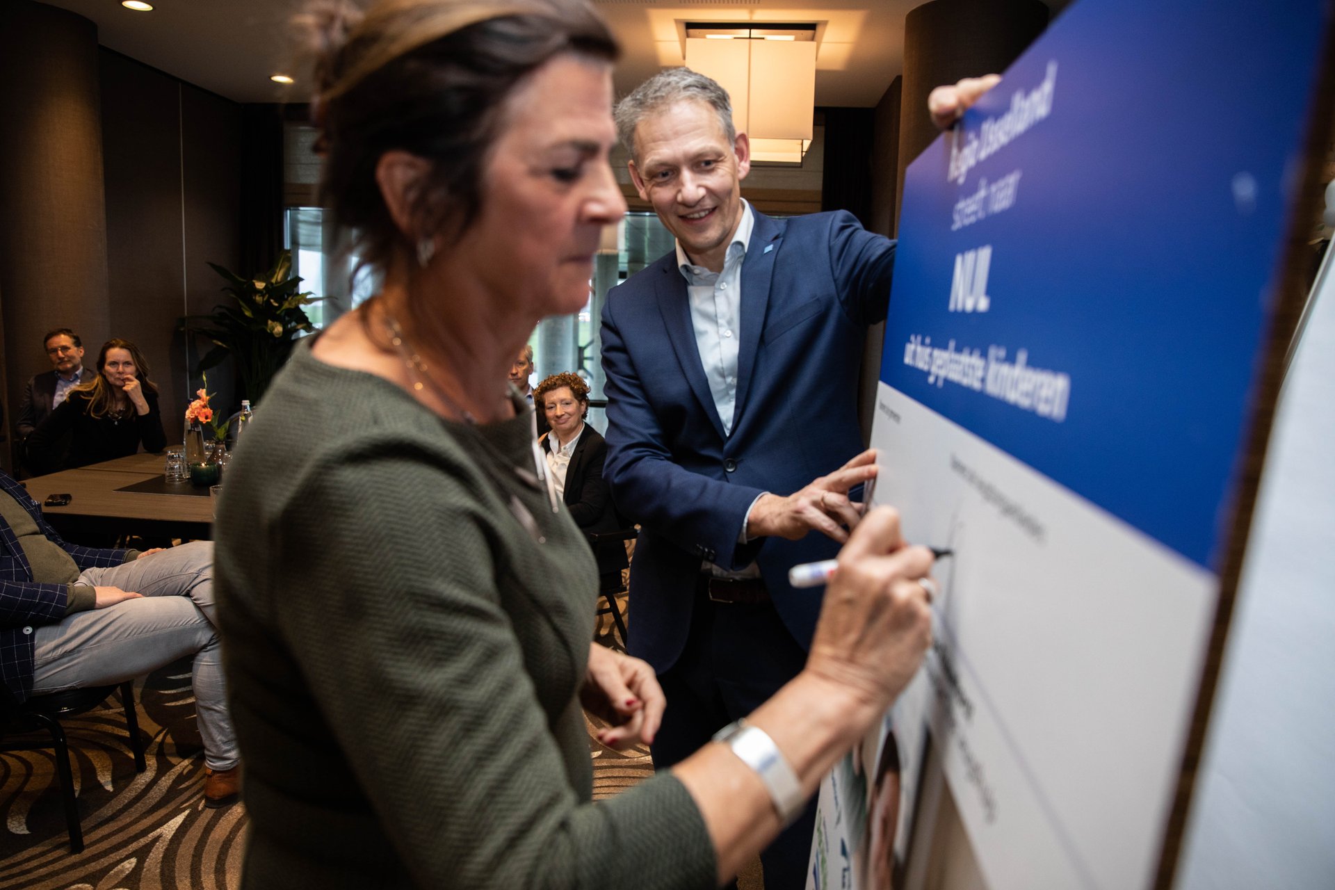 Foto: Louise Rouwhorst ondertekent het convenant namens de 17 jeugdzorgaanbieders, onder toeziend oog Michiel van Willigen. 