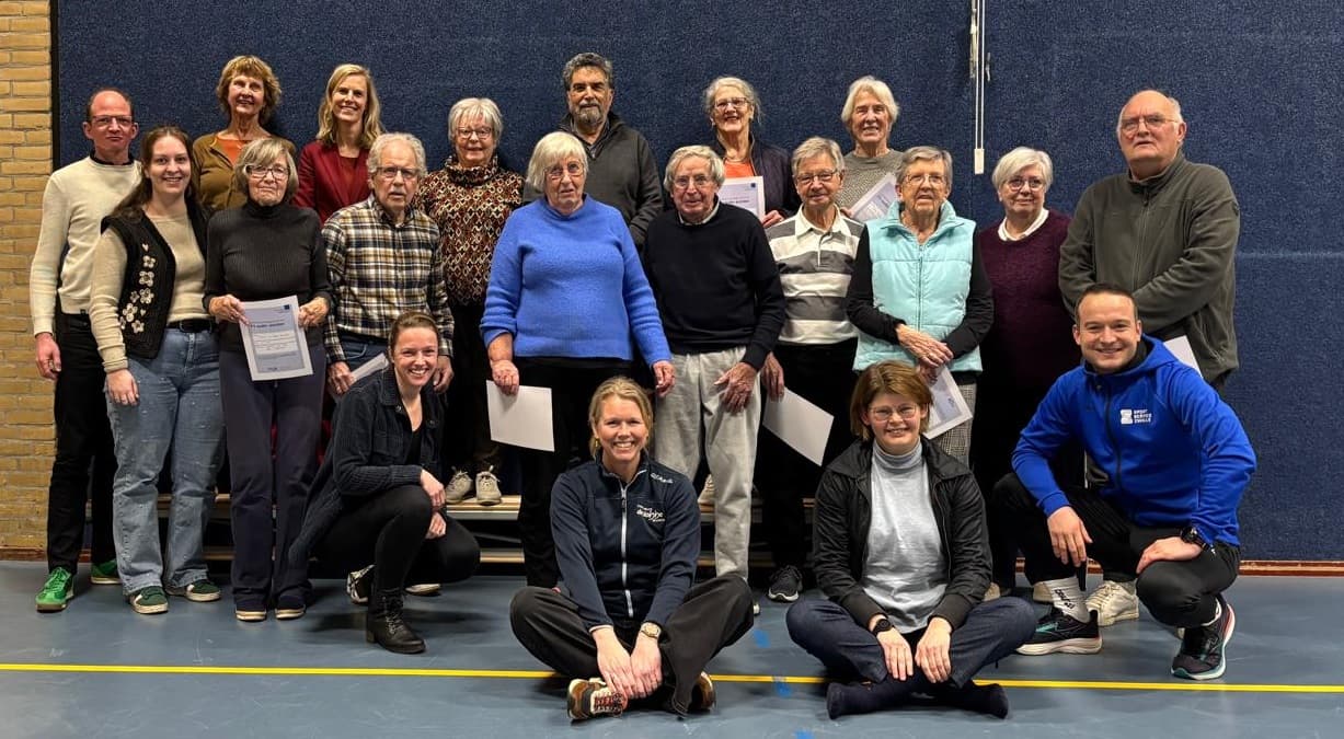 Groep oudere deelnemers van Fit Ouder Worden met begeleiding in een gymzaal